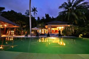 a swimming pool in front of a house at night at Villa Marley in Senggigi 