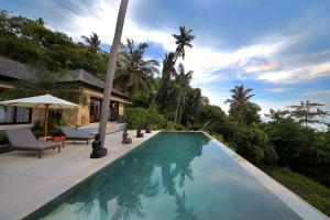 a swimming pool next to a house with palm trees at Villa Marley in Senggigi 