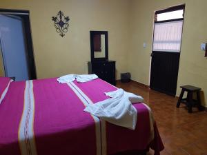 ein Schlafzimmer mit einem rosa Bett mit Handtüchern darauf in der Unterkunft Hotel Nuevo Cupatitzio in Uruapan del Progreso