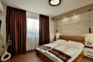 a bedroom with a large bed and a brick wall at Apartments Relax 1&2 in Varna City