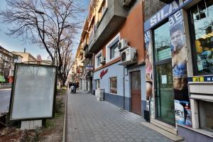 a city street with buildings and a sign on the sidewalk at Apartments Relax 1&2 in Varna City