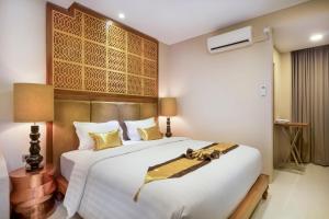 ein Schlafzimmer mit einem großen weißen Bett mit goldenen Akzenten in der Unterkunft Raintree Boutique Villa & Gallery in Yogyakarta