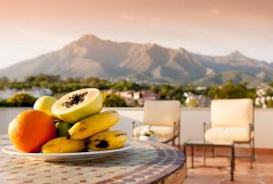 une assiette de fruits sur une table avec des montagnes en arrière-plan dans l'établissement Apartamentos Guadalpin Boutique, à Marbella