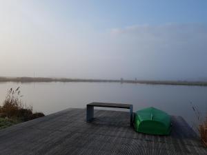 un banco sentado en un muelle junto a un lago en Ferienhaus Poseidon, en Neuharlingersiel