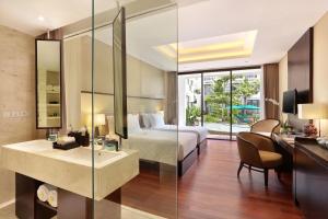 a bedroom with a bed and a desk and a sink at Bali Nusa Dua Hotel in Nusa Dua