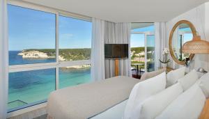 um quarto de hotel com uma cama e uma grande janela em Meliá Cala Galdana em Cala Galdana