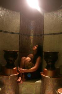 a woman sitting in a shower in a bathroom at The Club Hotel & Spa Jersey in Saint Helier Jersey