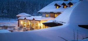 una casa coperta di neve di notte con luci di Wellness- und Vitalhotel Böhmhof a Bodenmais