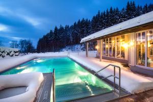 una piscina nella neve accanto a una casa di Wellness- und Vitalhotel Böhmhof a Bodenmais