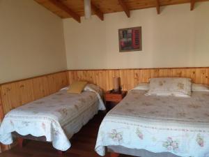 twee bedden in een kamer met houten wanden bij Hostal Balmaceda La Serena in La Serena