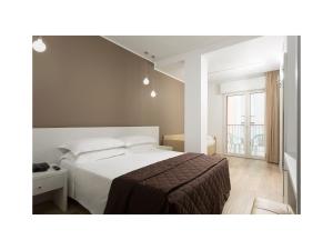 a bedroom with a white bed and a window at Hotel Gardenia in Lido di Jesolo