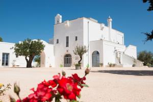 un edificio blanco con flores rojas delante de él en Masseria Le Torri, en Polignano a Mare