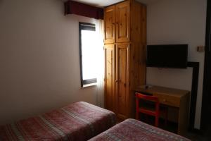 Cette chambre comprend un lit, un bureau et une télévision. dans l'établissement Hotel Dolomiti, à Passo del Tonale