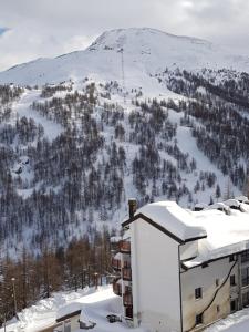 a building in the snow with a mountain in the background at Monolocale Milky Way - Sestriere in Sestriere