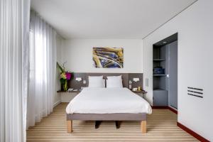 a bedroom with a white bed and white curtains at Novotel Suites Paris Montreuil Vincennes in Paris