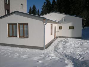 a white house with snow in front of it at Apartmán Srní in Srní