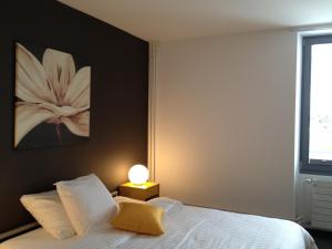 a bedroom with a bed with a white flower painting on the wall at Au Boeuf Rouge in Crassier