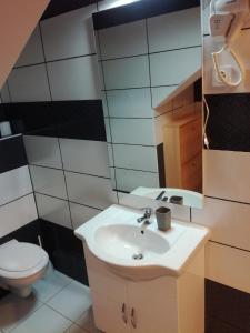 een badkamer met een wastafel, een toilet en een spiegel bij Guest House Kvartin in Umag