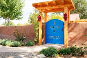 een blauwe poort in een tuin met een houten structuur bij Casa La Huerta in Albuquerque