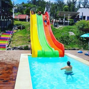 un uomo in una piscina con uno scivolo arcobaleno di Complejo Laderas del Cerro a Piriápolis