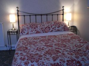 een slaapkamer met een rood en wit bed met 2 lampen bij Moraydale Guest House in Elgin