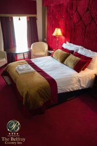 um quarto com uma cama grande e uma cabeceira vermelha em The Belfray Country Inn em Derry Londonderry