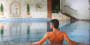 a shirtless man sitting in a swimming pool at Ringhotel Mönch`s Waldhotel in Unterreichenbach