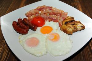 um prato de pequeno-almoço com ovos, salsicha e cogumelos em Hotel Hemera em Podgorica