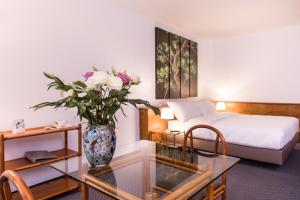 a bedroom with a bed and a vase with flowers on a glass table at Hotel Sagitta in Geneva