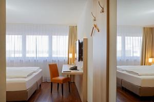 a hotel room with two beds and a desk and a tv at H+ Hotel Stuttgart Herrenberg in Herrenberg