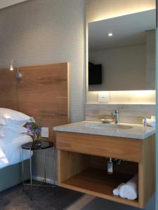 a bathroom with a sink and a mirror and a bed at Ocean Vista Boutique Guest House in Durban