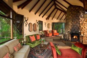 uma sala de estar com uma lareira de pedra e um sofá em Tsala Treetop Lodge em Plettenberg Bay