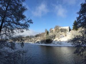 um edifício numa colina nevada junto a um rio em Hotel Bô Rivage em Neufchâteau