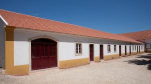 un edificio con puertas rojas y techo rojo en Quinta dos Álamos Agroturismo, en Golegã