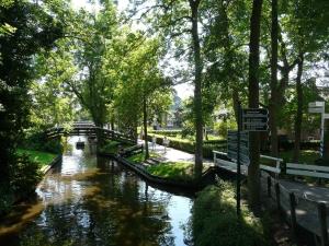 a river with a bridge in a park at De Galeriet Giethoorn in Giethoorn