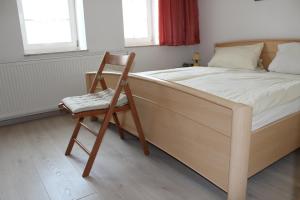 een slaapkamer met een bed en een houten stoel bij Alter Topf in Quedlinburg