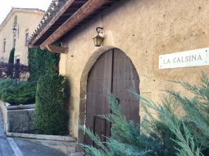 un bâtiment avec une porte en bois et un panneau indiquant la rue dans l'établissement Montserrat La Calsina, à Monistrol de Montserrat