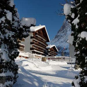 ein schneebedecktes Gebäude mit einem Berg im Hintergrund in der Unterkunft Hotel Residence in Grindelwald