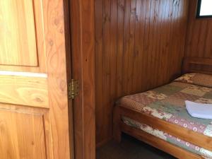 een kleine slaapkamer met een bed in een houten hut bij Hostal el Nogal Pucón in Pucón