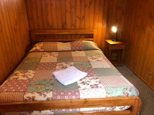 een slaapkamer met een bed met een quilt bij Hostal el Nogal Pucón in Pucón