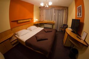 een slaapkamer met een bed, een bureau en een televisie bij Hotel Krona Domžale in Domžale