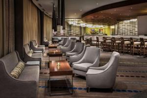 uma sala de espera com cadeiras e mesas e um bar em Hyatt Regency Pittsburgh International Airport em Clinton