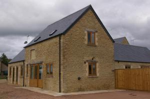 een stenen huis met een gambrel dak bij Ty Nant Cottages and Suites in Carterton