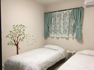 ein Schlafzimmer mit 2 Betten und einem Baumaufkleber an einem Fenster in der Unterkunft Nara Guesthouse Kaede in Nara