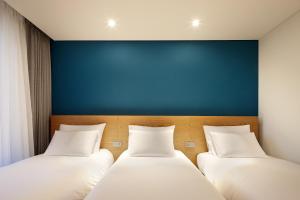 two beds in a room with a blue wall at L7 HONGDAE by LOTTE in Seoul