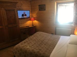 1 dormitorio con 1 cama y TV en la pared en B&B Gressoney, en Gressoney-la-Trinité