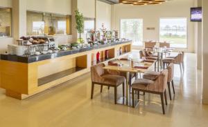 un restaurant avec un comptoir doté de tables et de chaises dans l'établissement Hotel Naveen Lakeside, à Hubli