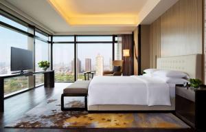 una camera da letto con un grande letto bianco e una grande finestra di Grand Hyatt Shenyang a Shenyang