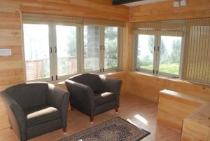 twee stoelen in een kamer met ramen bij Relaxing 2 B/R Estate House, Deenaty, Tamil Nadu in Coimbatore