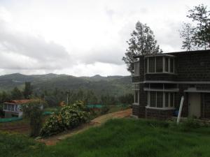 een huis op een heuvel met bergen op de achtergrond bij Relaxing 2 B/R Estate House, Deenaty, Tamil Nadu in Coimbatore